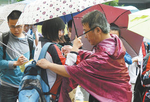 　一名家长在雨中为考生背上书包。 　　本报记者 万程鹏摄