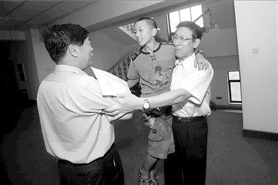 校长(右)抱着廖葳和书记(左)握手。记者张沫摄 校长(右)抱着廖葳和书记(左)握手。记者张沫摄